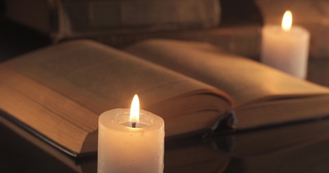A Burning Candles and an Old Book. Reading and teaching by candlelight at night.