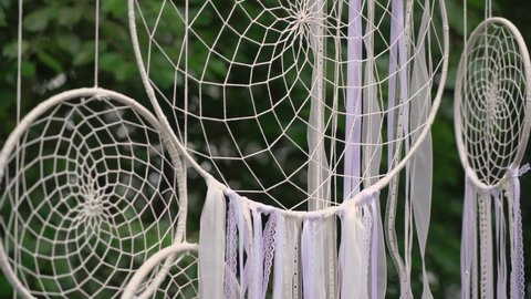 Dream catchers. White wicker dyed ribbons dreamcatcher hang outside in the garden or backyard. Mystical rites, isoterics.