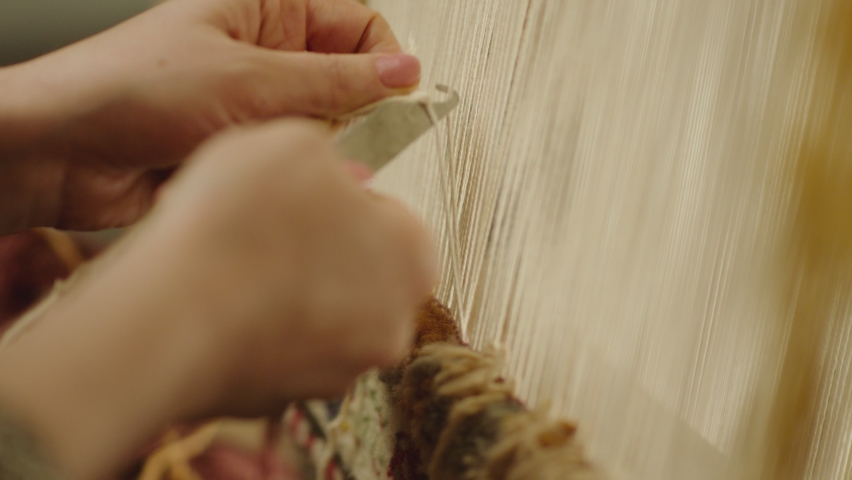A Woman weaving traditional Asian carpet . Handmade carpet embroidery . Women 's hands create a pattern using multi-colored threads . Close up view . Weaving machine . Needlework . Carpet-makers  Royalty-Free Stock Footage #1085027950
