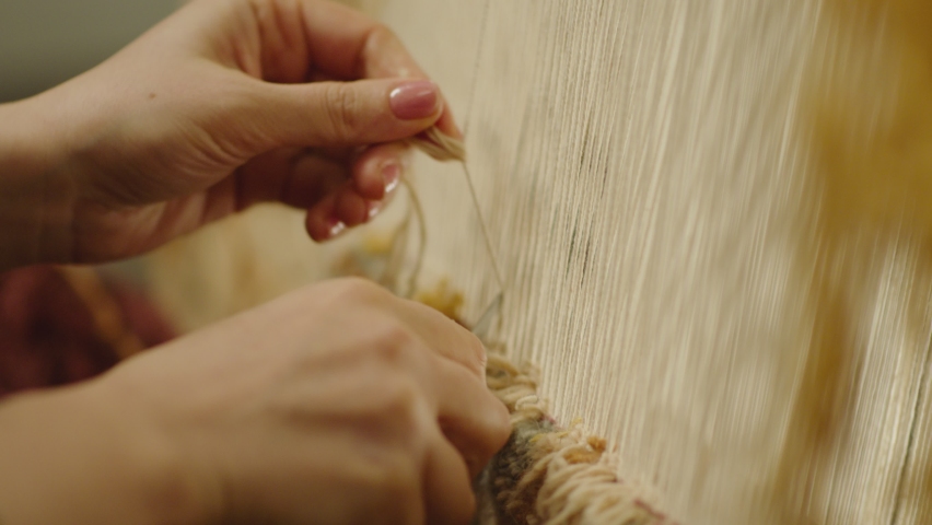 A Woman weaving traditional Asian carpet . Handmade carpet embroidery . Women 's hands create a pattern using multi-colored threads . Close up view . Weaving machine . Needlework . Carpet-makers  | Shutterstock HD Video #1085027950