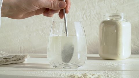 Putting a teaspoon of whey protein powder into a glass of water and stirring it, slow motion