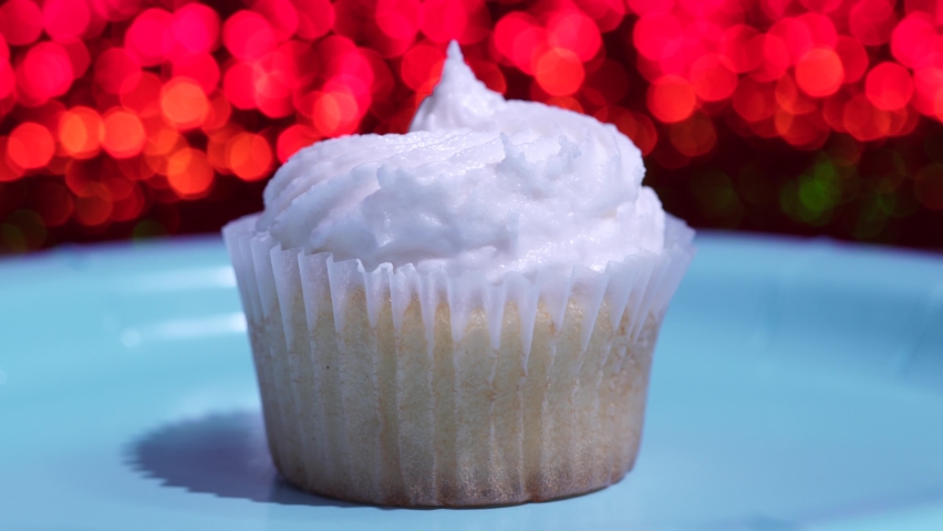 Cupcake macro shallow depth of field and decoration with sugar sprinkles. Cup cake with white vanilla cream on red background. Process of making delicious desserts muffin for birthday or Valentine.