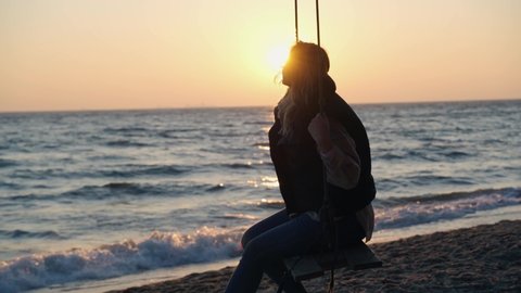 A lady on the swing in slow motion during a scenic sunrise at the beach in Gdynia, Poland-shot in 4K