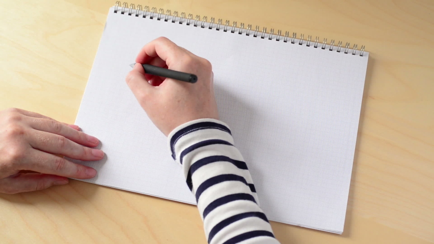 A high angle time lapse of a person writing in a notebook