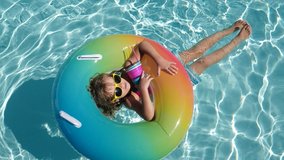 Happy kid playing with colorful swim ring in swimming pool on summer day. Child water toys. Children play in tropical resort. Family beach vacation. - Powered by Shutterstock - Get 15% off with code: PIKWIZARD15
