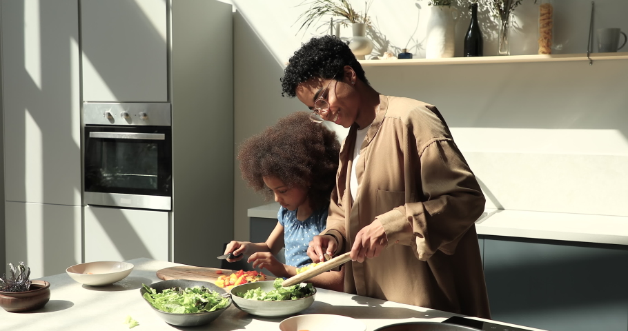 Beautiful woman her 10s daughter preparing together natural healthy vegetarian salad. Loving mom share skill and family recipe to cute girl. Good life habit, natural food delivery services ad concept