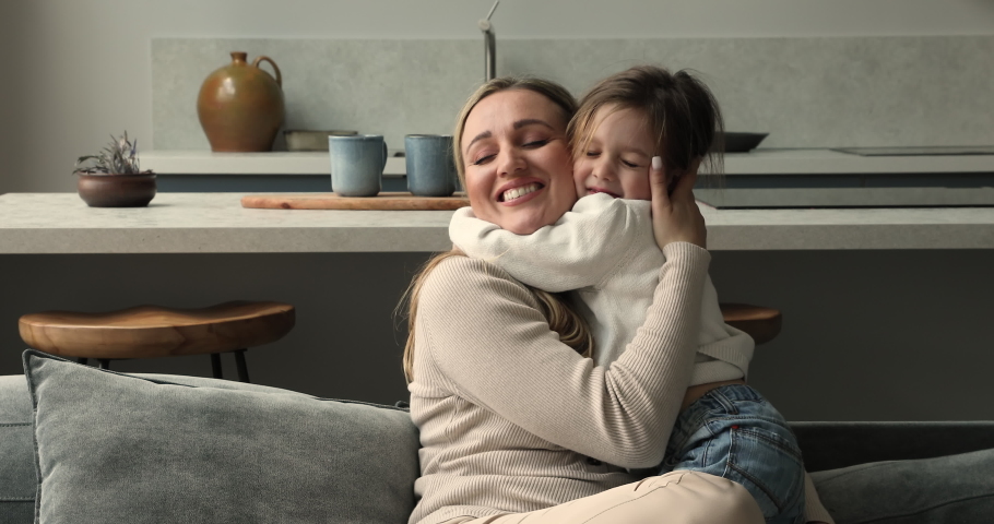 Beautiful young woman cuddling tightly her cute little 5s daughter, loving family sit on sofa hugging showing love, they missed each other after long separation. Happy motherhood, Mother Day concept Royalty-Free Stock Footage #1085053882