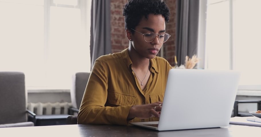 Nervous tired African woman in glasses sit at desk work on laptop, make urgent task, faced with lack of idea and understanding. Creative crisis, stuck on problem solution, information overload concept Royalty-Free Stock Footage #1085056223