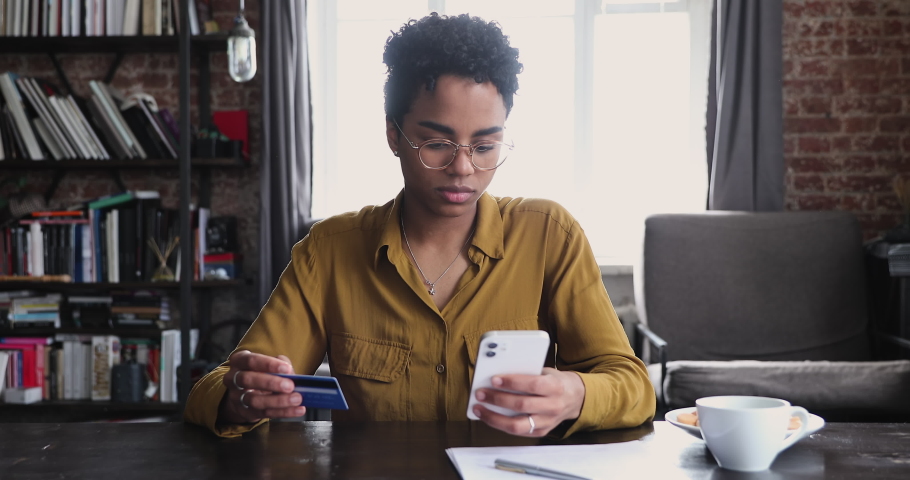 African woman holds debit card and cellphone try to make e-payment through e-bank app, having online ecommerce shopping problem, balance of funds on card not sufficient to pay order, overspend concept Royalty-Free Stock Footage #1085056256