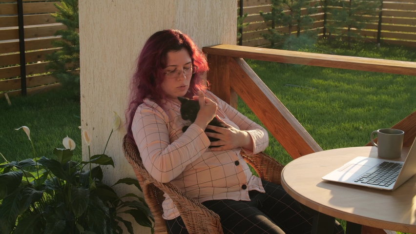 Friendship and pets concept. Little black kitten in the arms of a young woman