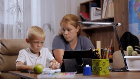 A frustrated mom and her sad little son hold a video conference with a teacher during distance learning during the coronavirus outbreak.
