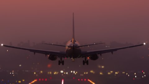 Scenic view of the night cityscape with a plane landing. Big passenger airliner arriving to the single runway airport as seen from the terminal. High quality 4k footage