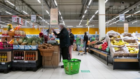 People shopping in supermarket, time lapse. Crowd of shoppers with shopping carts in large distribution network. Moscow, Russia - December 03, 2021.