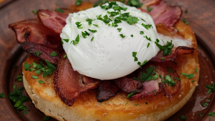 Toast with poached egg and bacon close up. Cutting poached egg with runny egg yolk over toast . Healthy breakfast or lunch food Royalty-Free Stock Footage #1085064413