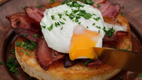 Toast with poached egg and bacon close up. Cutting poached egg with runny egg yolk over toast . Healthy breakfast or lunch food