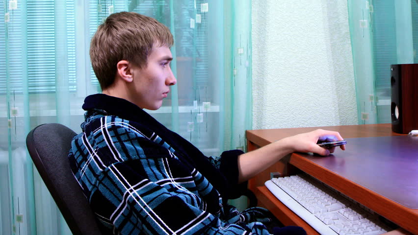 young man talking on the phone and playing on the computer. dolly shot