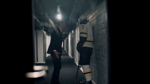 Angry disappointed coach yelling on ice hockey player in the hallway near rink. Shoot with 2x anamorphic lens