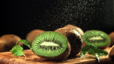 Splashes of water fall on the sliced kiwi. On a black background.Filmed is slow motion 1000 frames per second. High quality FullHD footage
