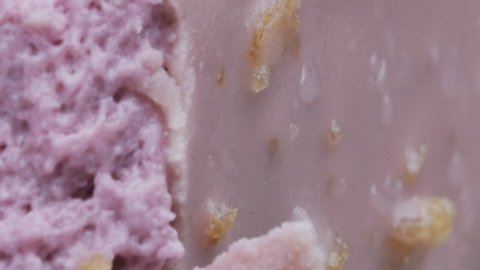a steel spoon cuts off a piece of purple ice cream. Extreme close-up, showing the texture of the dessert.