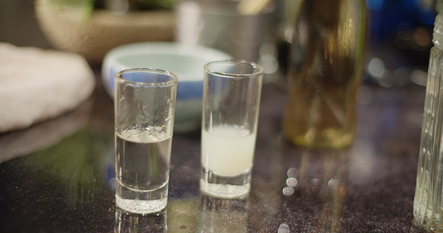Cocktail series. Bartender preparing a Peruvian cocktail called Pisco Sour, in a bar with a relaxed atmosphere in slow motion, add ice, lime and mix the drink wearing black gloves as biosecurity 
