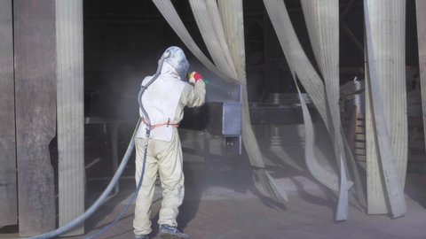 The sandblaster in protective suit and helmet is sandblasting new metal construction. High quality 4k footage