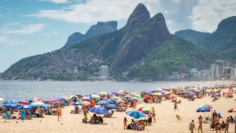 Rio de Janeiro, Brazil - December 9, 2021: Dolly left time lapse sequence showing people enjoying the summer at famous Ipanema beach in Rio de Janeiro, Brazil. 