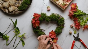 Florist decorates floral wreath for Valentines day. Hand crafted Valentines day home decor. Table top view, POV.  - Powered by Shutterstock - Get 15% off with code: PIKWIZARD15