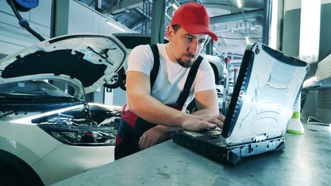 Automobile service, car mechanic. Auto mechanic uses a laptop while conducting diagnostics test