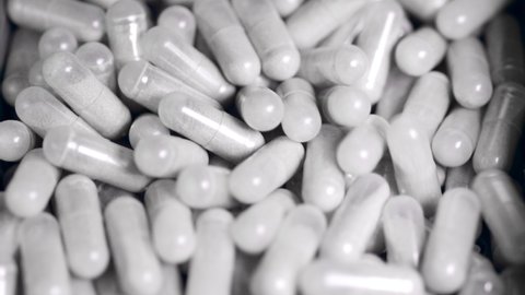 Close up of capsules with powdered medication moving in a pile