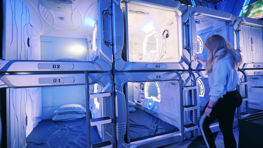 A girl is climbing up into the capsule hotel room