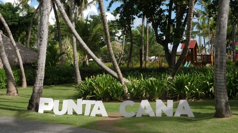White wooden sign Punta Cana in the garden with palm trees, nobody