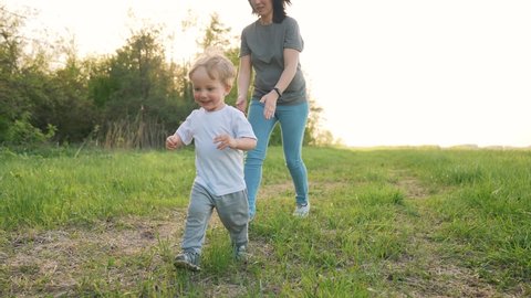 Happy kid run in park. Mom and baby play outdoors. Happy family concept. Smile of a baby. Kid play in park. Happy family in park. Kid smile and run. Baby dream. Mom and baby family games.