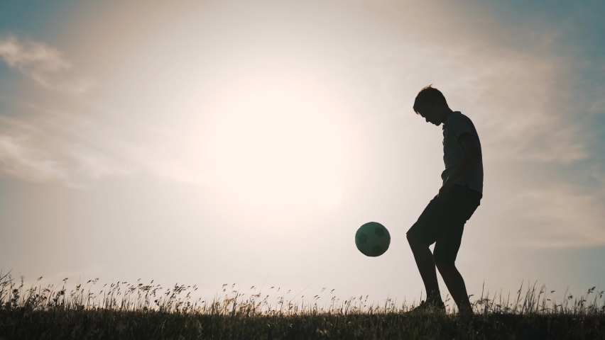 Boy with soccer ball. Child in park plays at sunset.Boy juggles soccer ball.Child dream of football match.Sports training in park. Sportsman is in control of ball. Child juggles ball.Healthy lifestyle | Shutterstock HD Video #1085100362
