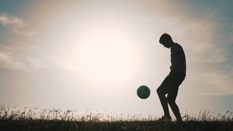 Boy with soccer ball. Child in park plays at sunset.Boy juggles soccer ball.Child dream of football match.Sports training in park. Sportsman is in control of ball. Child juggles ball.Healthy lifestyle