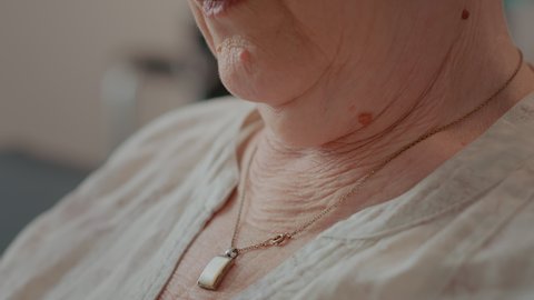 Senior woman with natural wrinkles of old age wearing glamour necklace. Retired person with wrinkled and loose skin having jewellery with gem over neckline. Pensioner aging. Close up