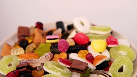 close-up of child's hand taking one gelatin candy, gummy bear, colored gelatinous sweets, black licorice candies, unhealthy food concept, halal gelatin, selective focus at shallow depth of field