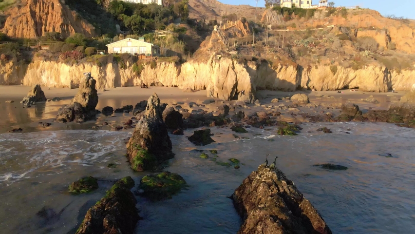 Aerial view of waves rolling into the shore at El Matador Beach during golden hour, Malibu California