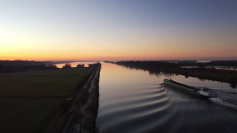 Aaerial view on a ship sailing on the river Ijssel during sunrset during a cold winter afternoon in Overijssel, Netherlands.