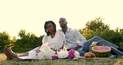 Black loving couple drinking wine on summer picnic