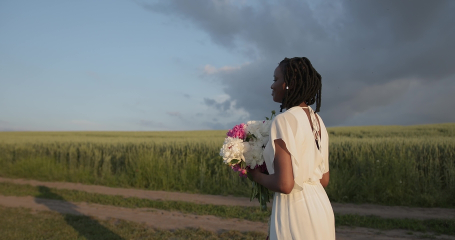 Beautiful black woman with flowers walk in the field