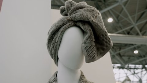 Gray soft towel on the head of a white mannequin woman in a store. Shot in motion