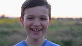 Portrait of a cute brunette boy at sunset in a field. Concept of children's emotions, video portrait