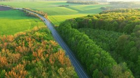 Picturesque footage of a country road passing through agricultural land from a bird's eye view. Location agrarian region Ukraine, Europe. Cinematic drone shot. Filmed in UHD 4k video. Beauty of earth.