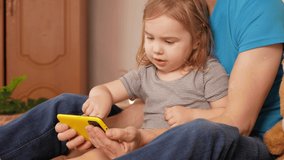 Father and daughter watch cartoon on phone, home interior, training. Smartphone with internet, funny video. Modern technology, bedroom.