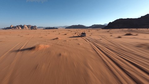 Стоковое видео: FPV chasing a 4x4 with tourists during the sunrise in the desert of Wadi Rum, Jordan