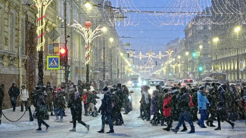 SAINT-PETERSBURG, RUSSIA - JANUARY 04 2022: Center of the city - Nevskii prospect, snowy day.
City traffic, pedestrians walking across road, heavy snowfall.