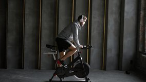 Caucasian man riding stationary exercise bike and listening motivated music in Bluetooths headphones.  Young strong man working out for keep fit and healthy. Motivation and strength  - Powered by Shutterstock - Get 15% off with code: PIKWIZARD15