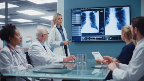 Hospital Conference Meeting Room: Female Physician Presents Patient X-Ray on TV Screen, Team of Medical Doctors Discuss Patient Treatment. Research Scientists Talk of Cure, Drug, Medicine Development