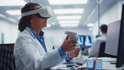 Futuristic Medical Hospital: Black Female Neurosurgeon Wearing Virtual Reality Headset Uses Controllers to Remotely Operate Patient with Medical robot. MRI Image Show Treatment of Neurological Disease