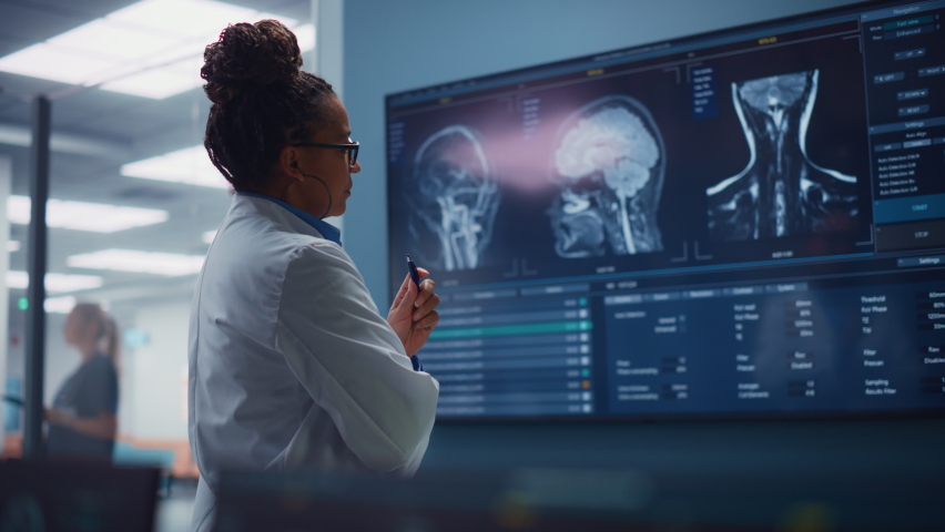 Medical Science Hospital: Confident Black Female Neurologist, Neuroscientist, Neurosurgeon, Looks at TV Screen with MRI Scan with Brain Images, Thinks about Sick Patient Treatment Method. Saving Lives Royalty-Free Stock Footage #1085128262
